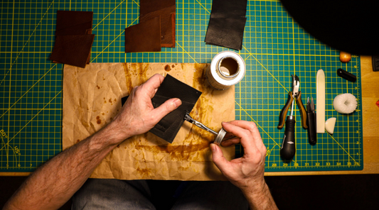 hands applying glue to piece of leather over workbench making a Dry Fly Leather Good